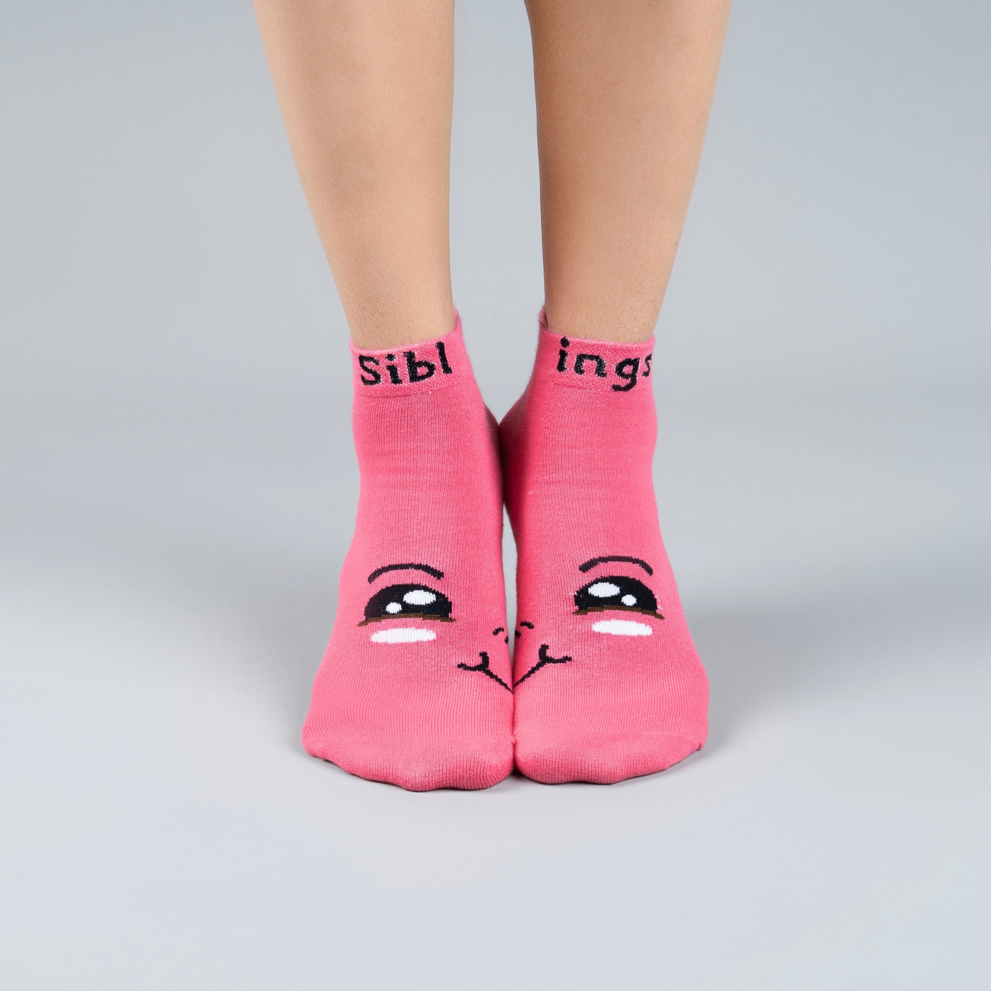 Pink socks with cartoon face design and text on a gray background