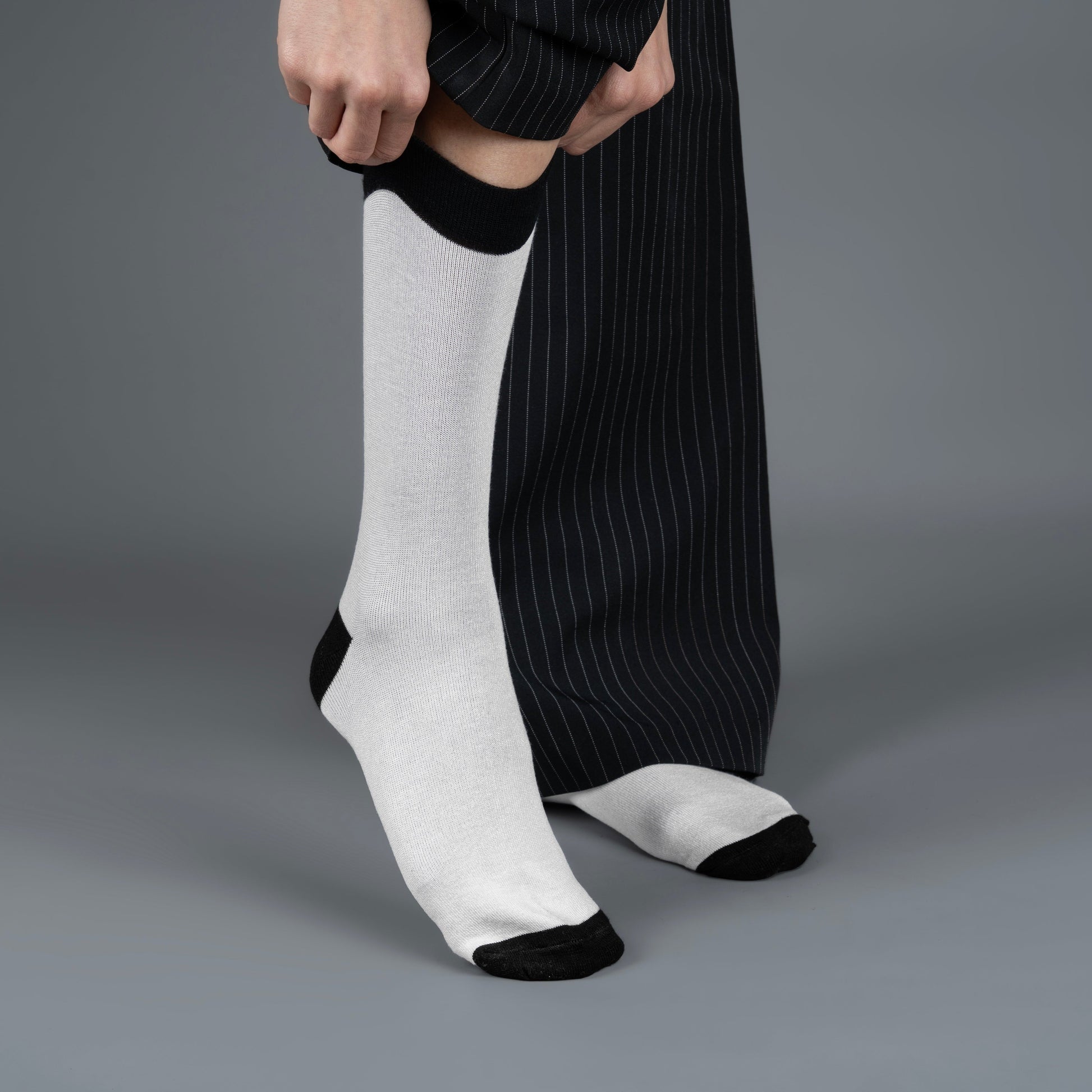 Person wearing black and white crew length bamboo socks on a gray background