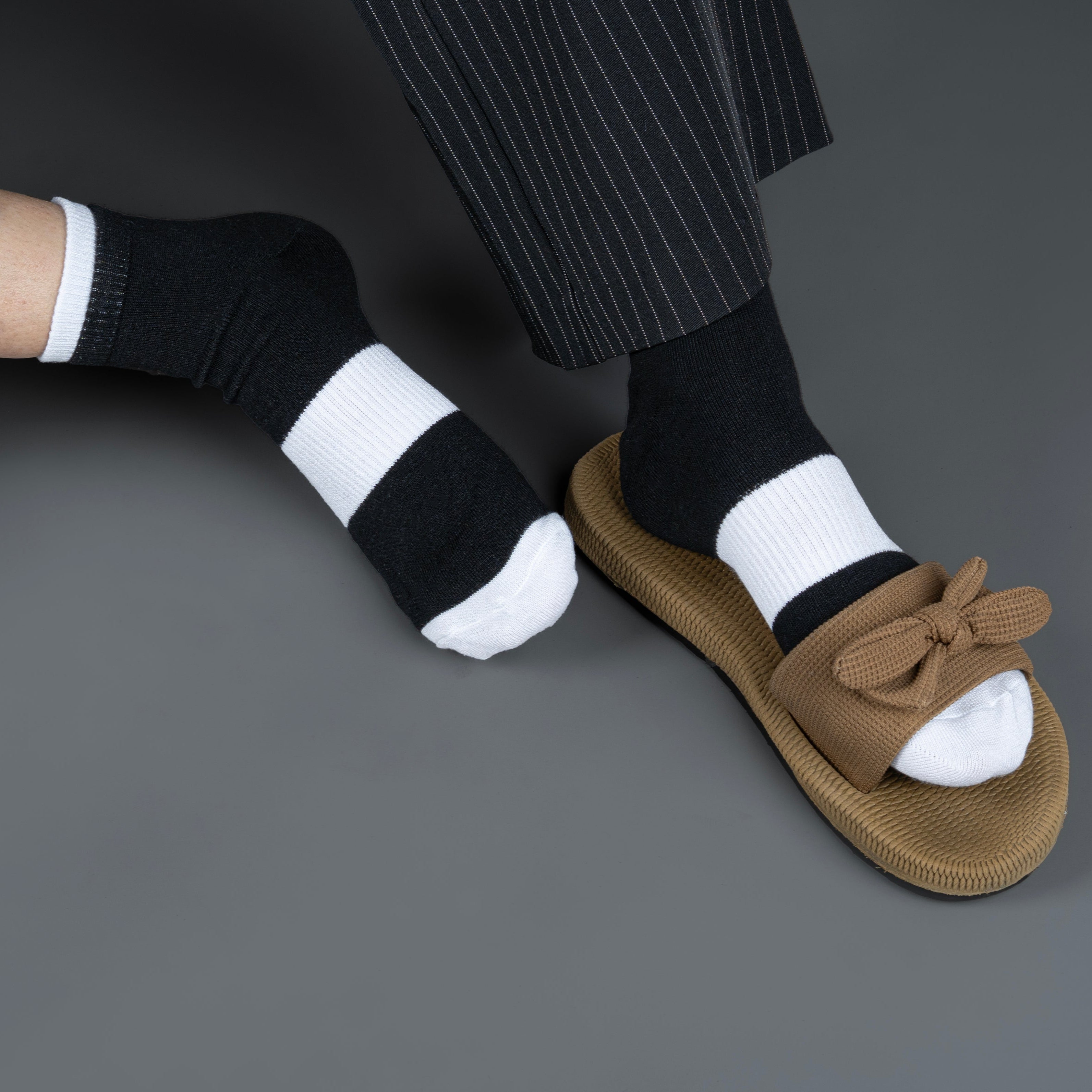 Brown sandal and black bamboo socks with a bow on a gray background