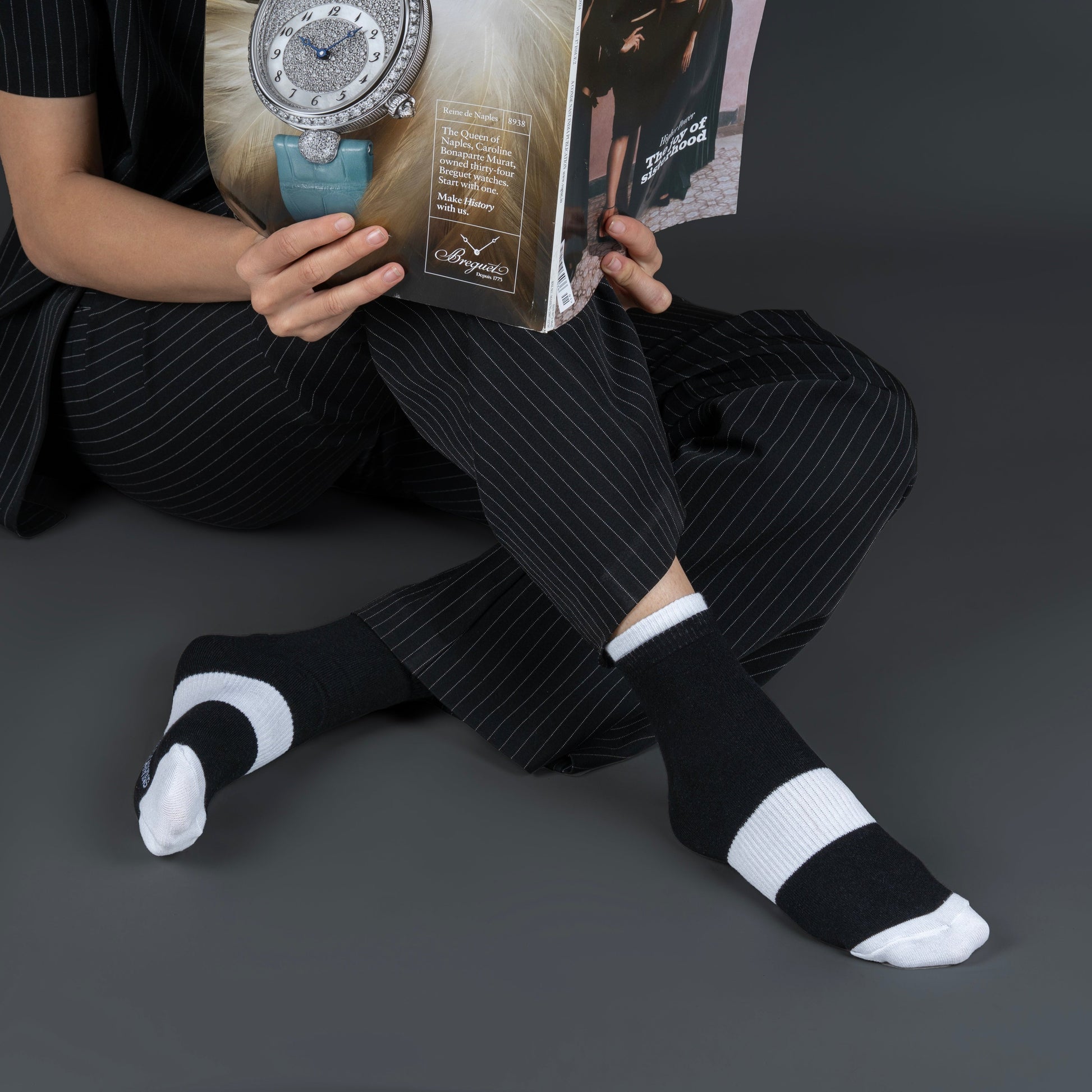 Person sitting on the ground wearing black and white bamboo socks with a dark background