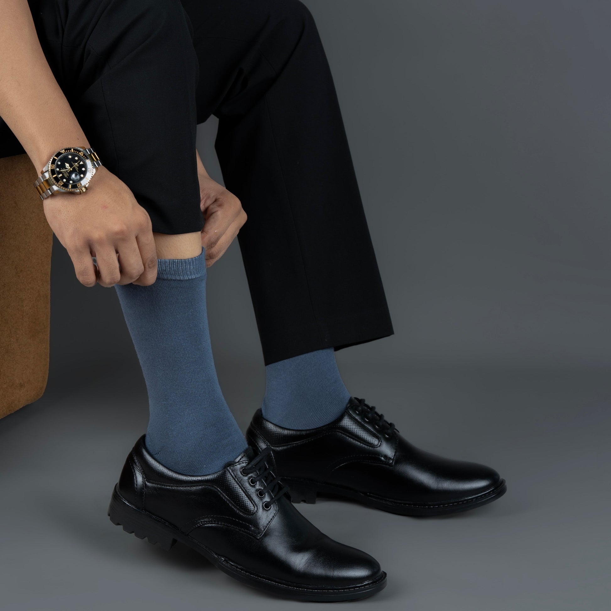 Person wearing black shoes, dark pants, and bombay gray bamboo socks on a gray background