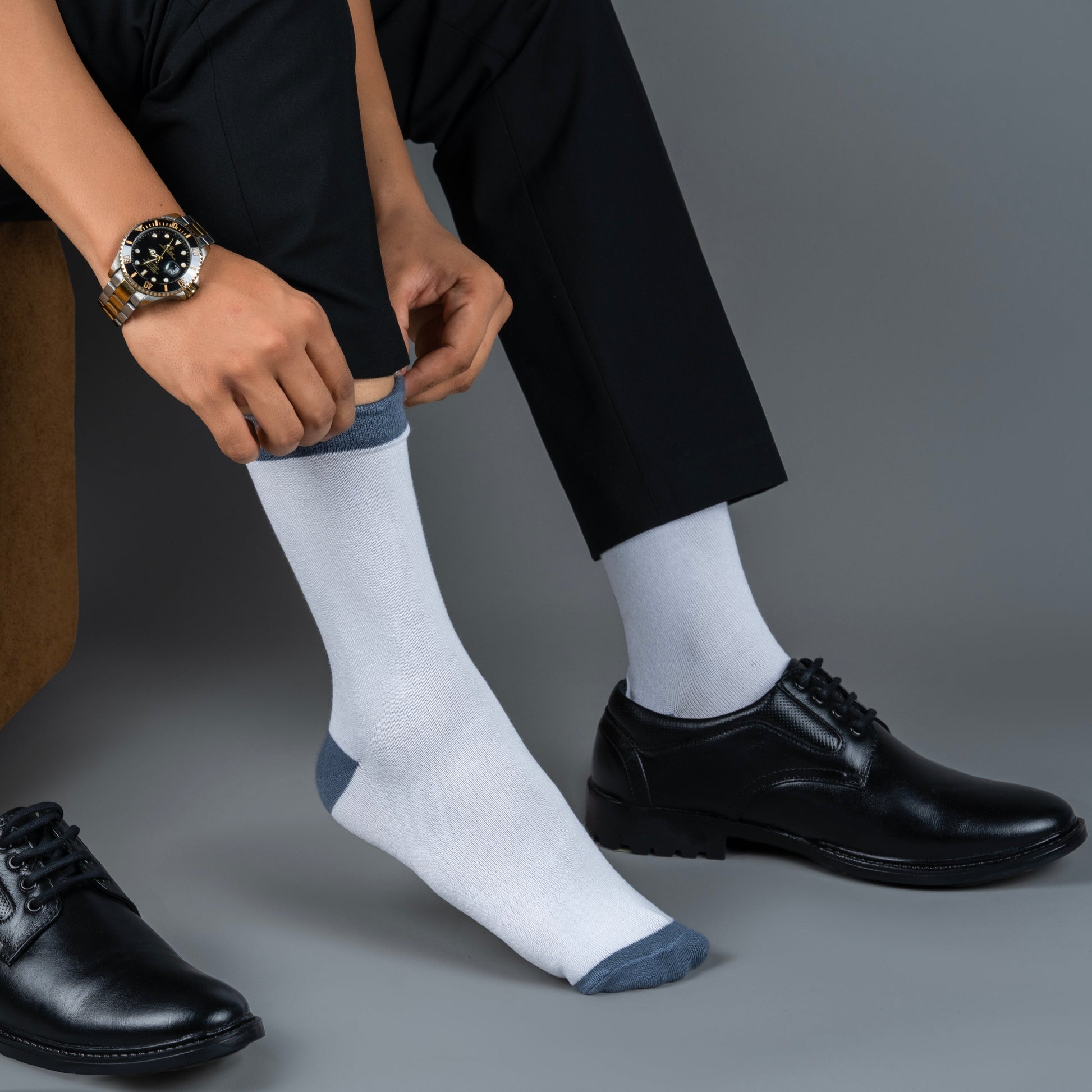 Person wearing black dress shoes and white bamboo socks with a gray background