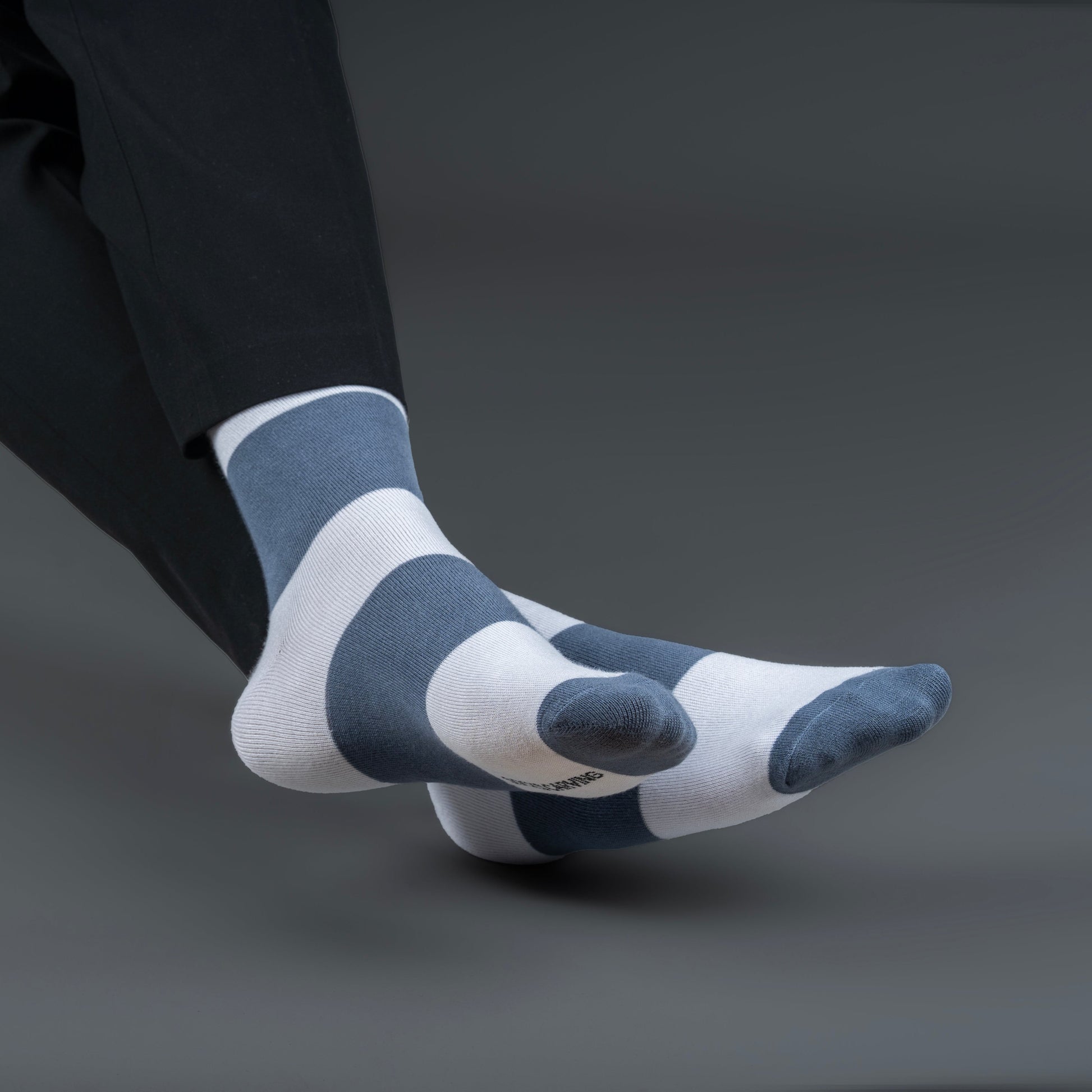 Person wearing and white striped bamboo socks on a gray background