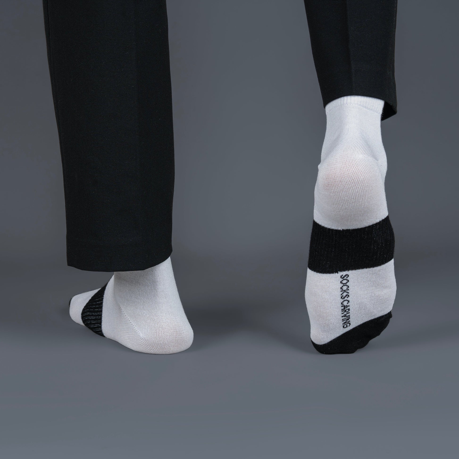 White bamboo socks with black accents worn by a person in a suit on a gray background