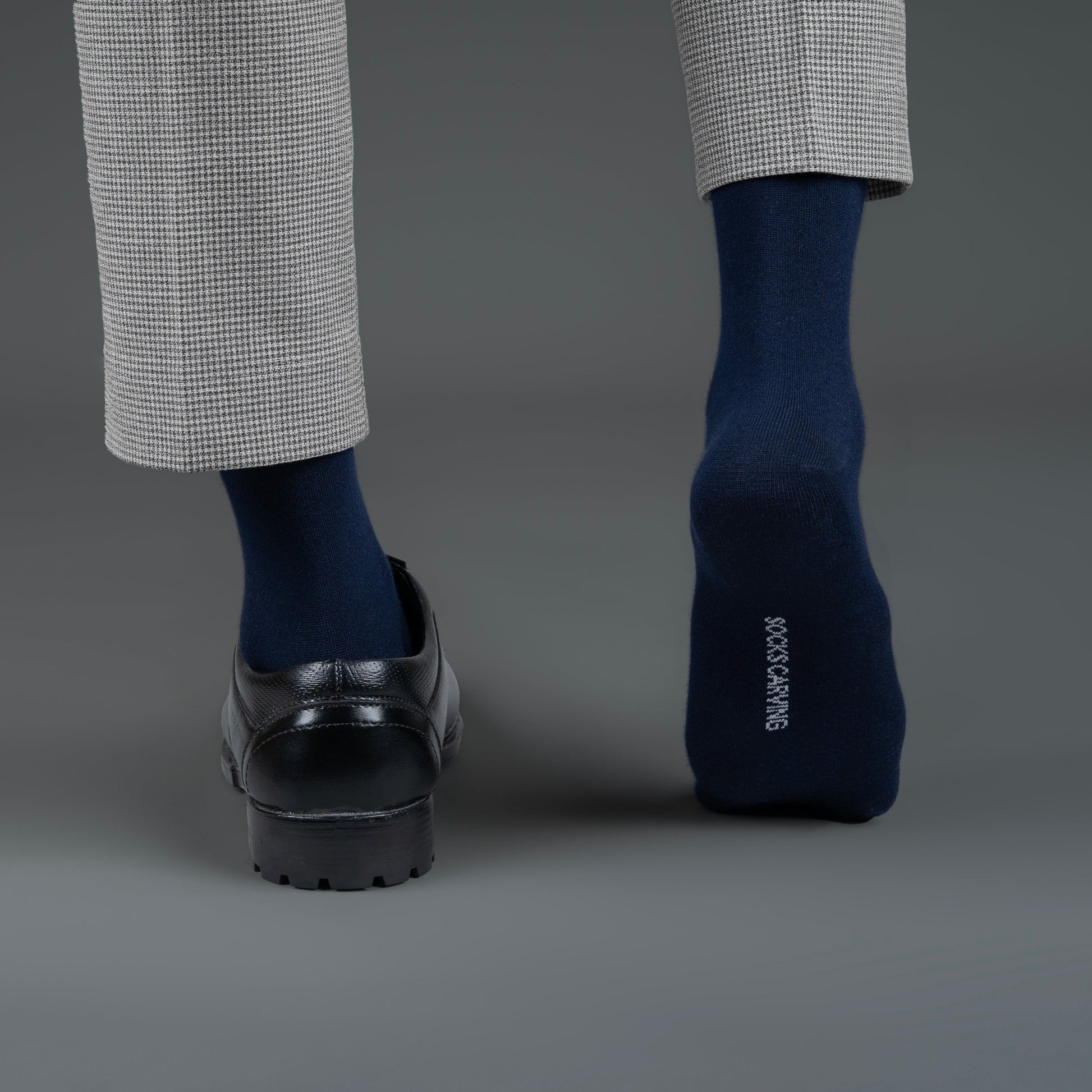 Person wearing navy bamboo socks with a gray background