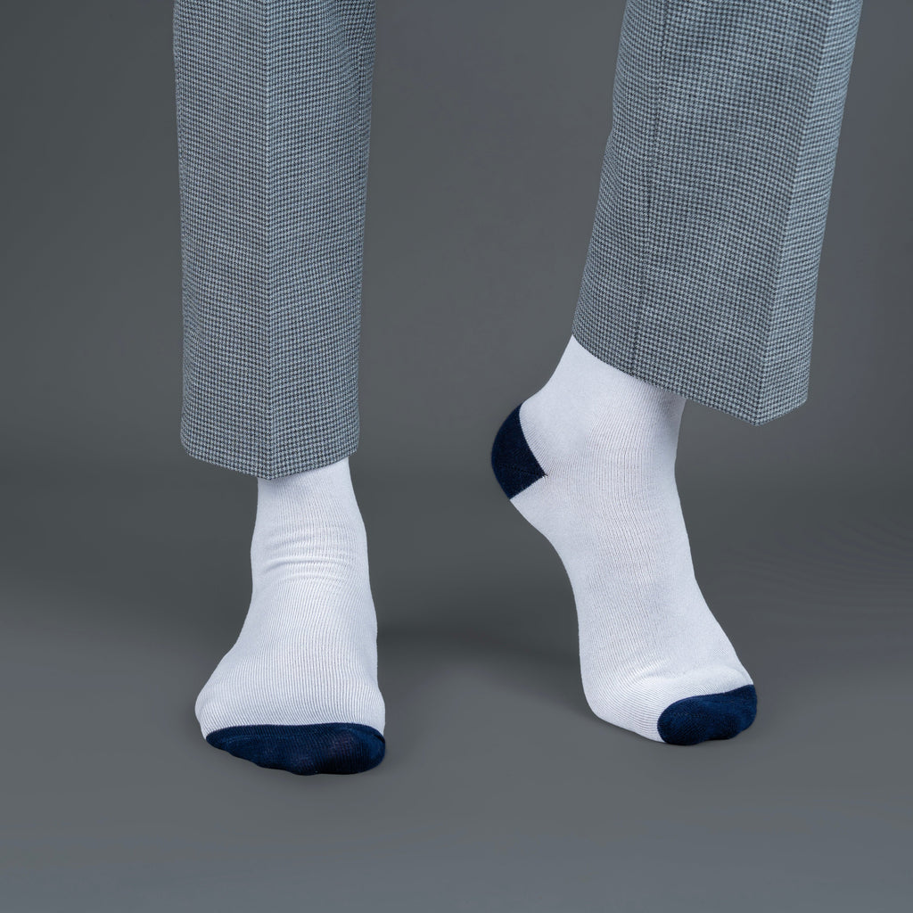 White socks with blue toes and cuffs worn with gray checkered pants on a gray background