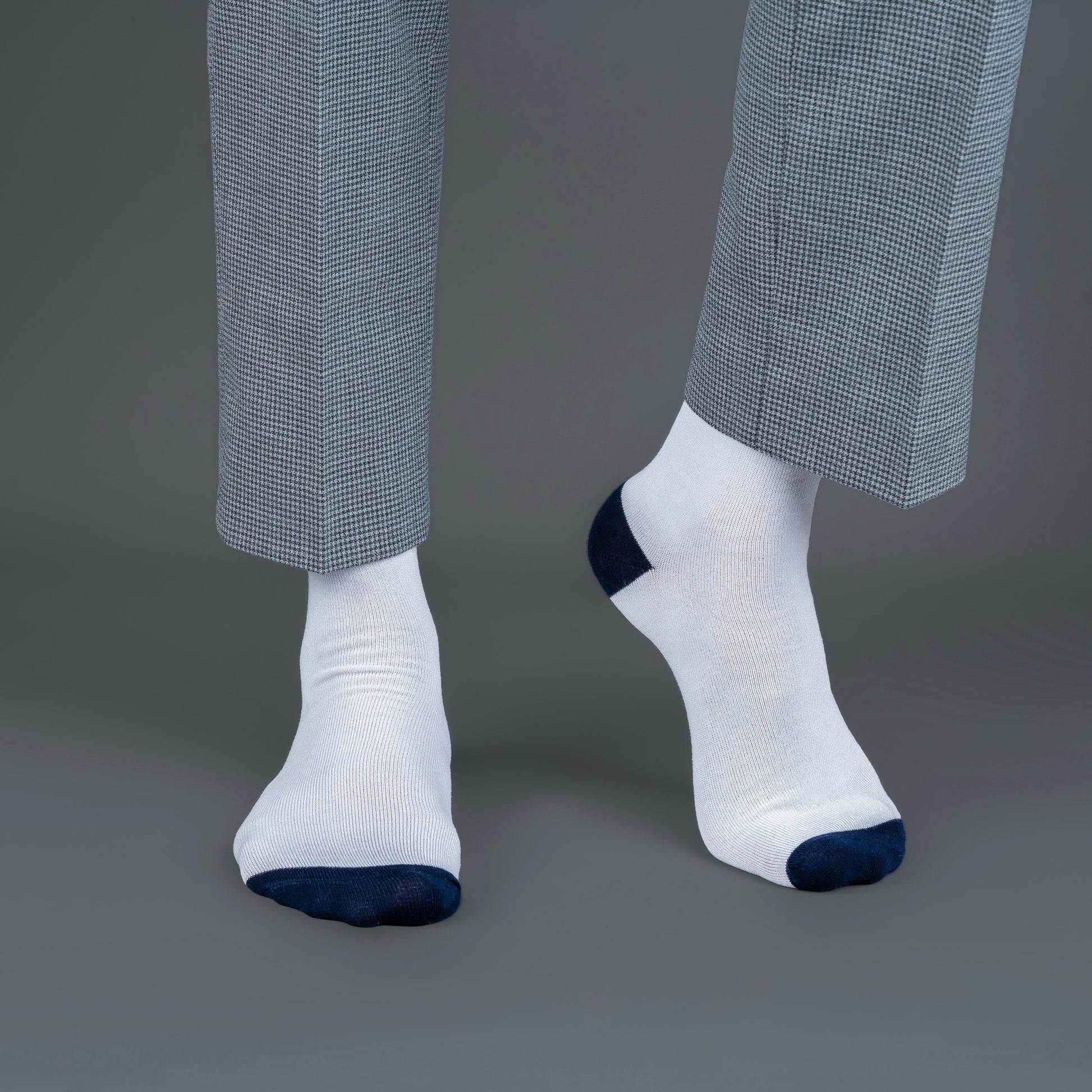 White socks with blue toes and cuffs worn with gray checkered pants on a gray background