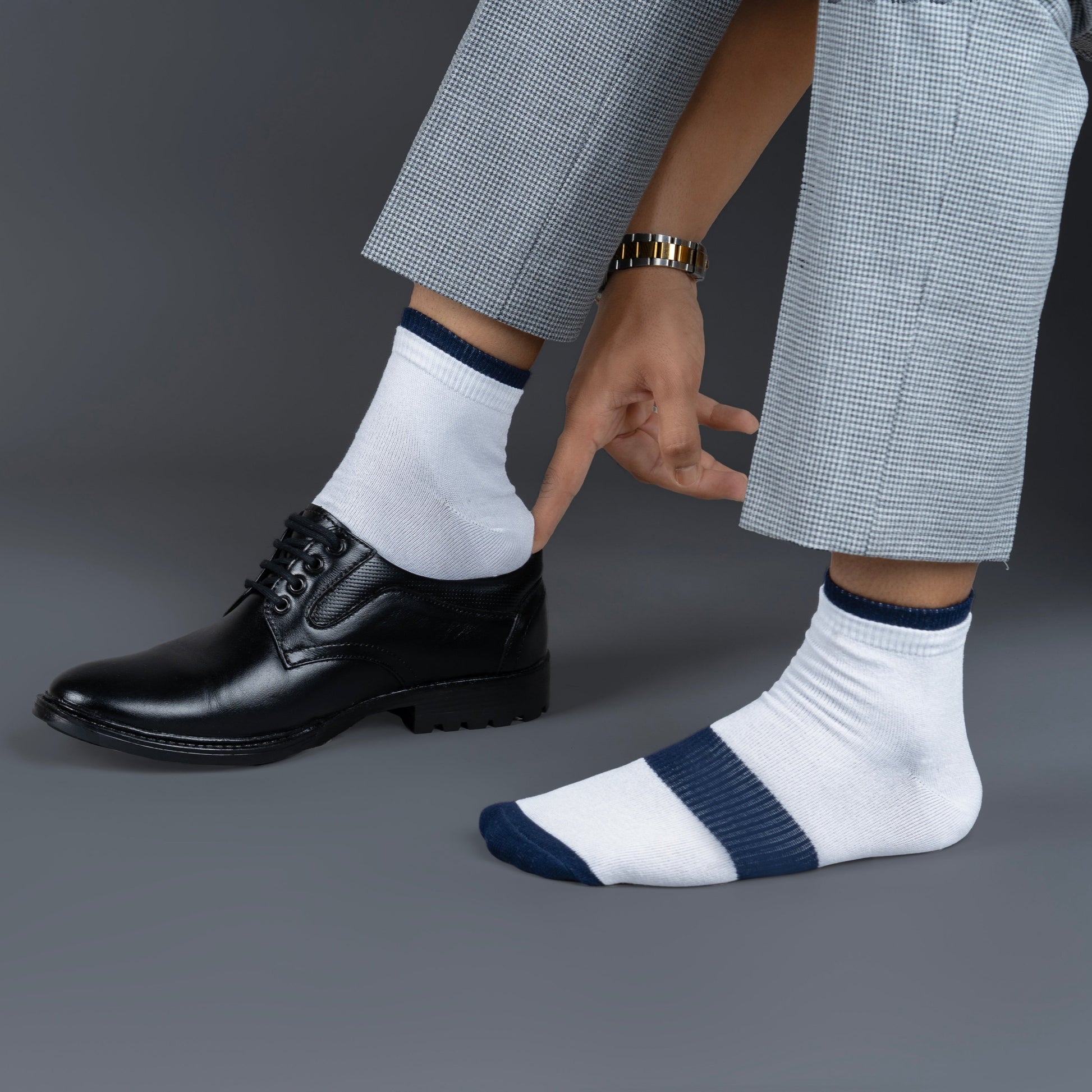 Person wearing black dress shoes and white bamboo socks with dark stripes on a gray background