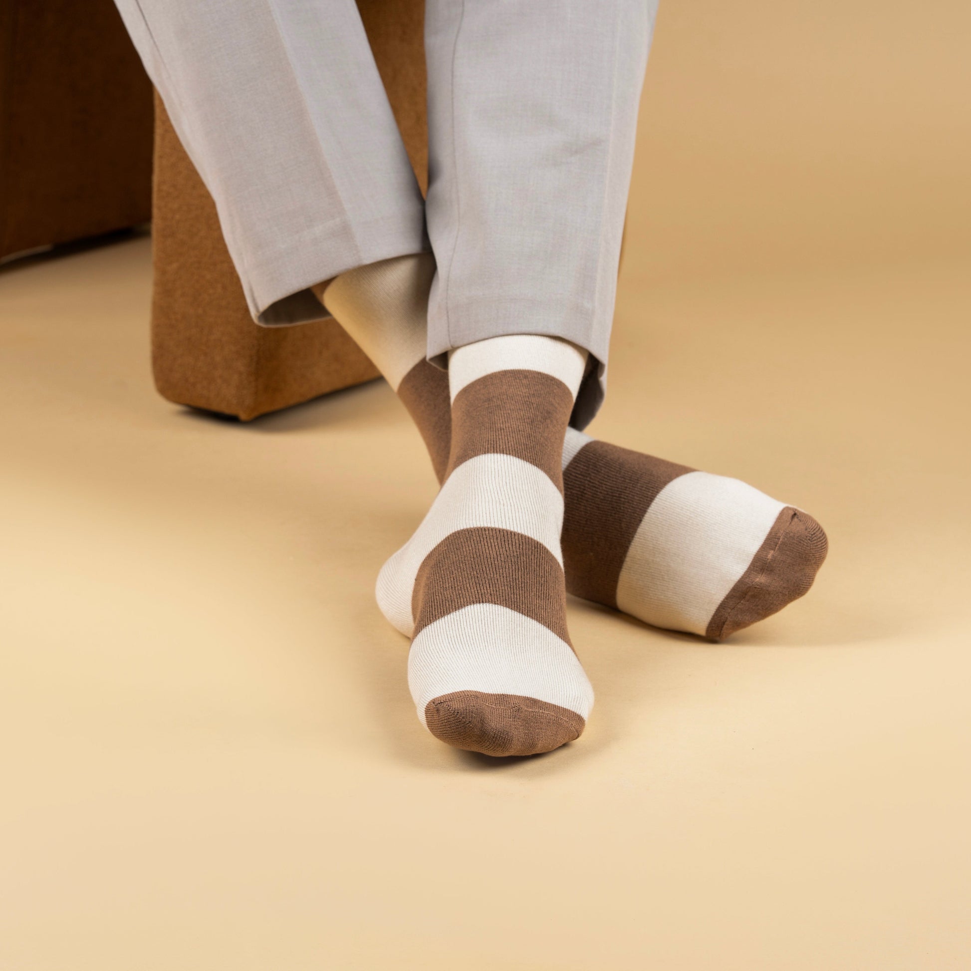 Brown and white striped bamboo socks worn by a person sitting on a beige couch.