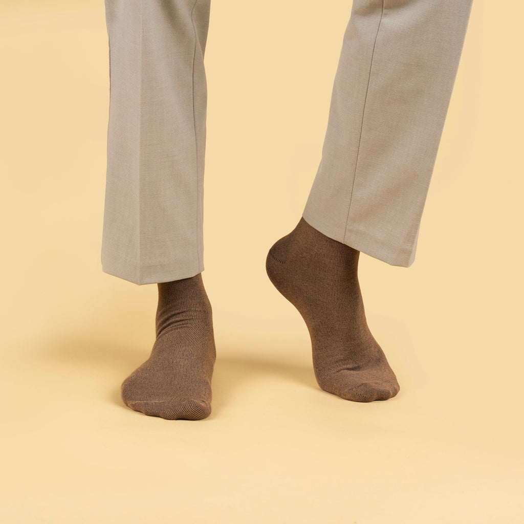 Brown socks worn with light gray pants on a beige background