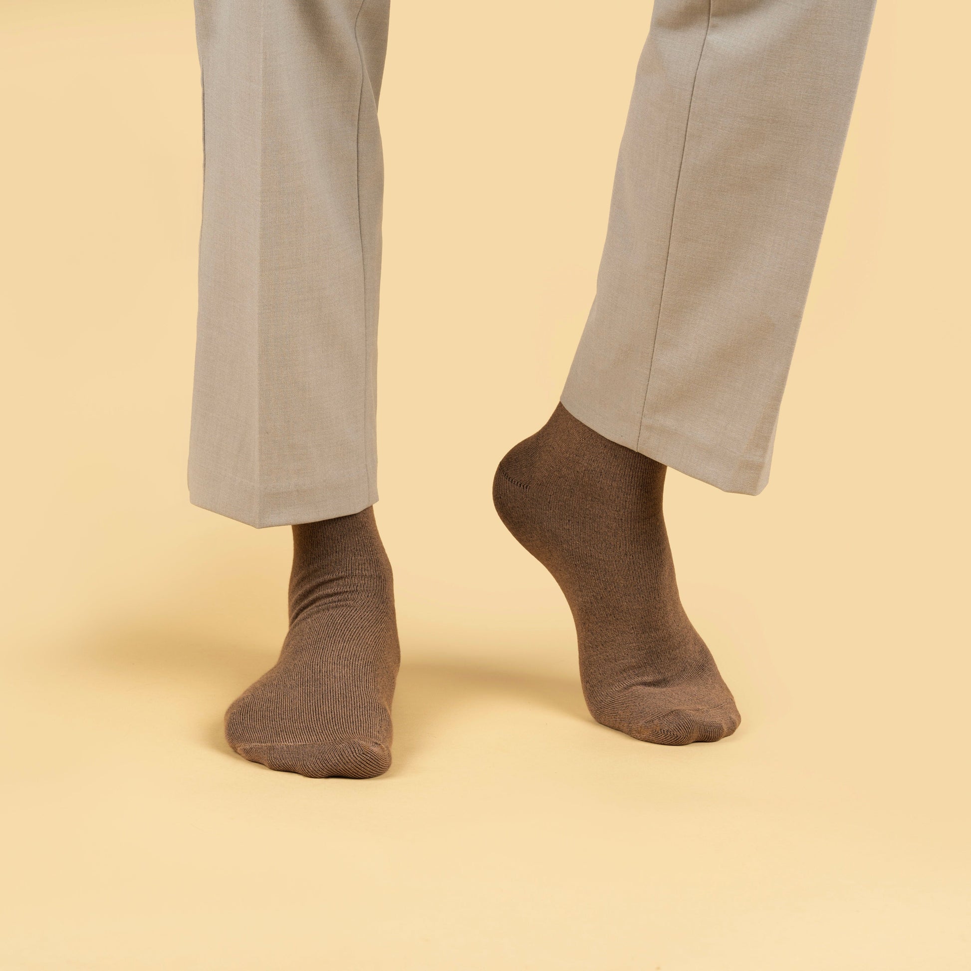 Brown socks worn with light gray pants on a beige background