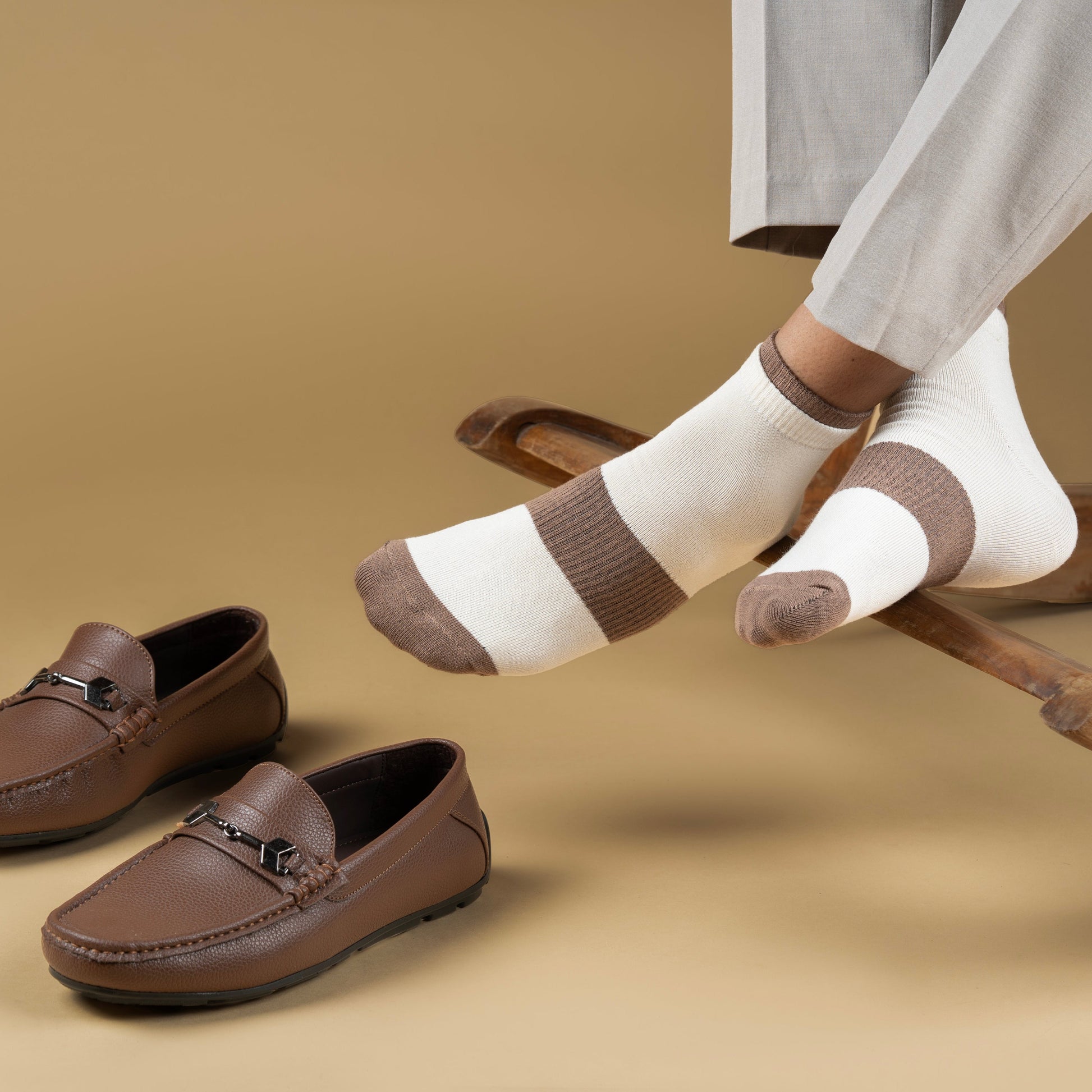 Brown loafers and striped bamboo socks on a beige background