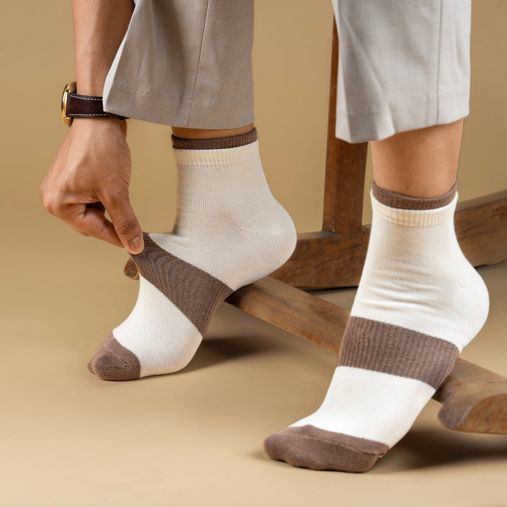 Person wearing white socks with brown accents on a beige background