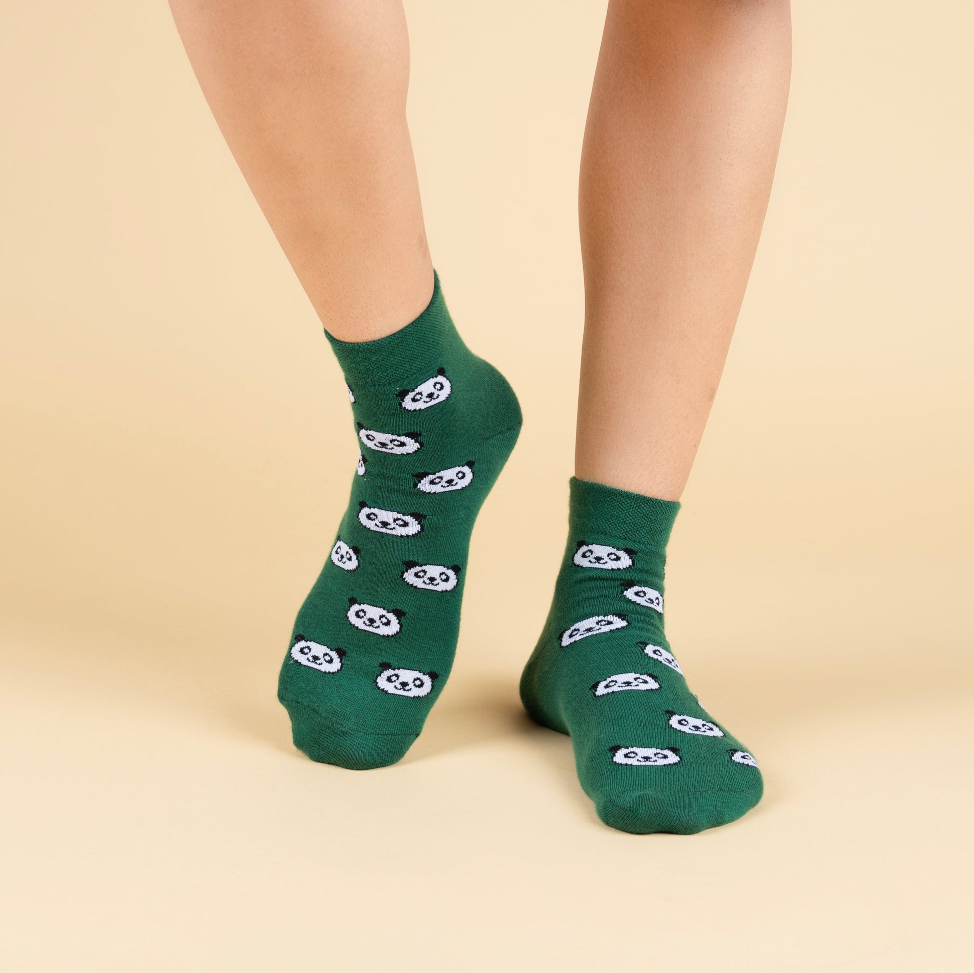 Green socks with panda design worn by a person on a beige background