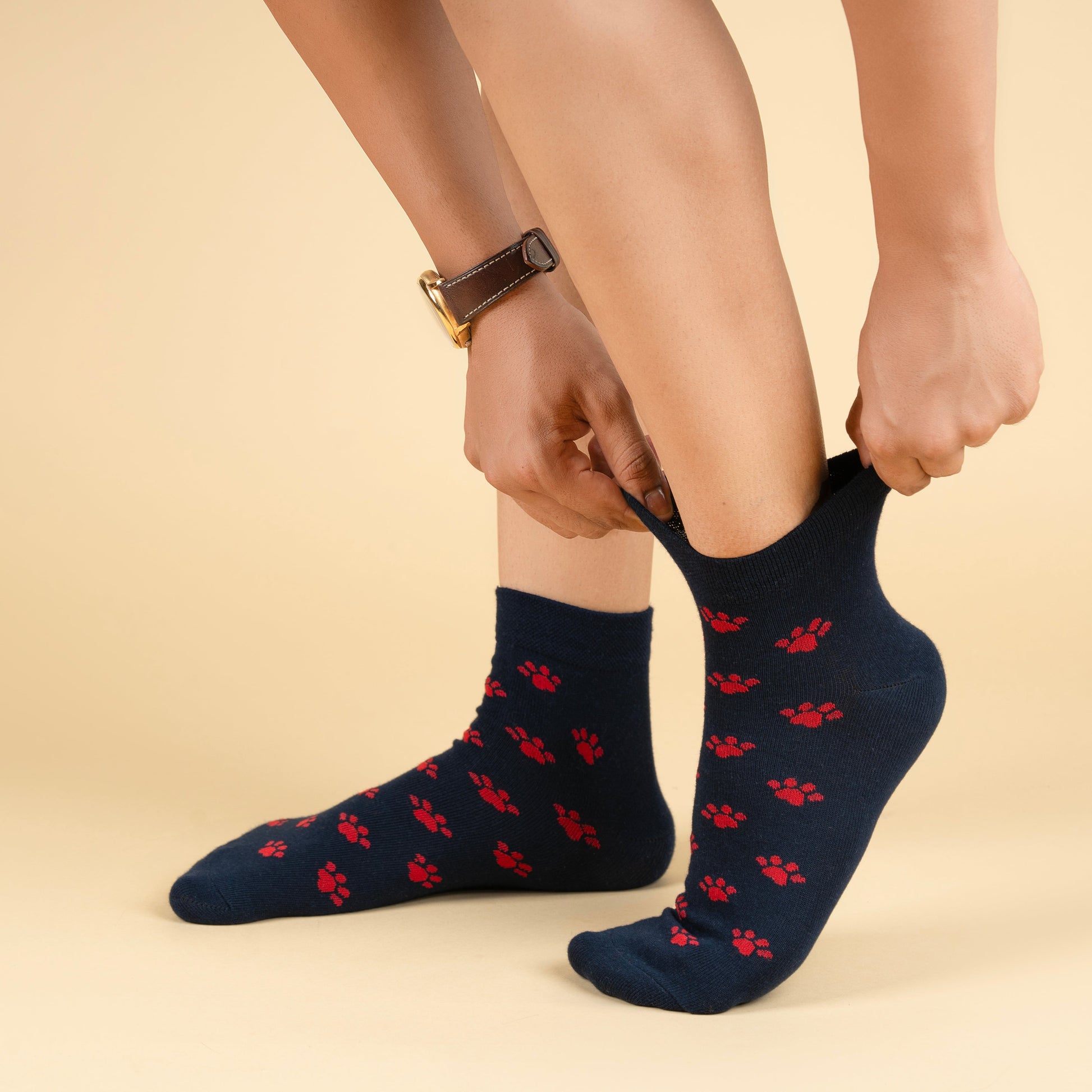 Person wearing navy socks with red paw prints on a beige background
