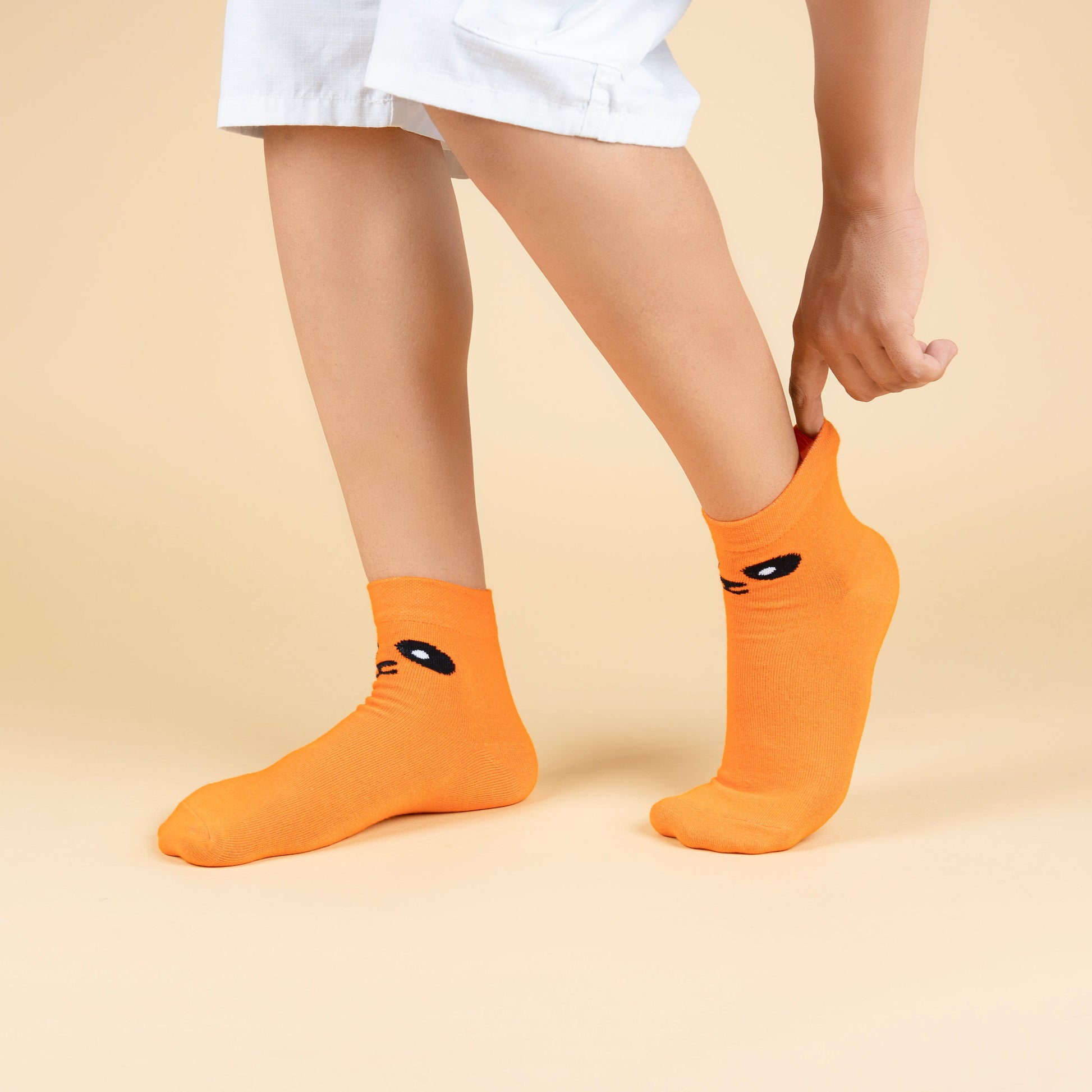 Person wearing orange socks with black cat faces on a beige background