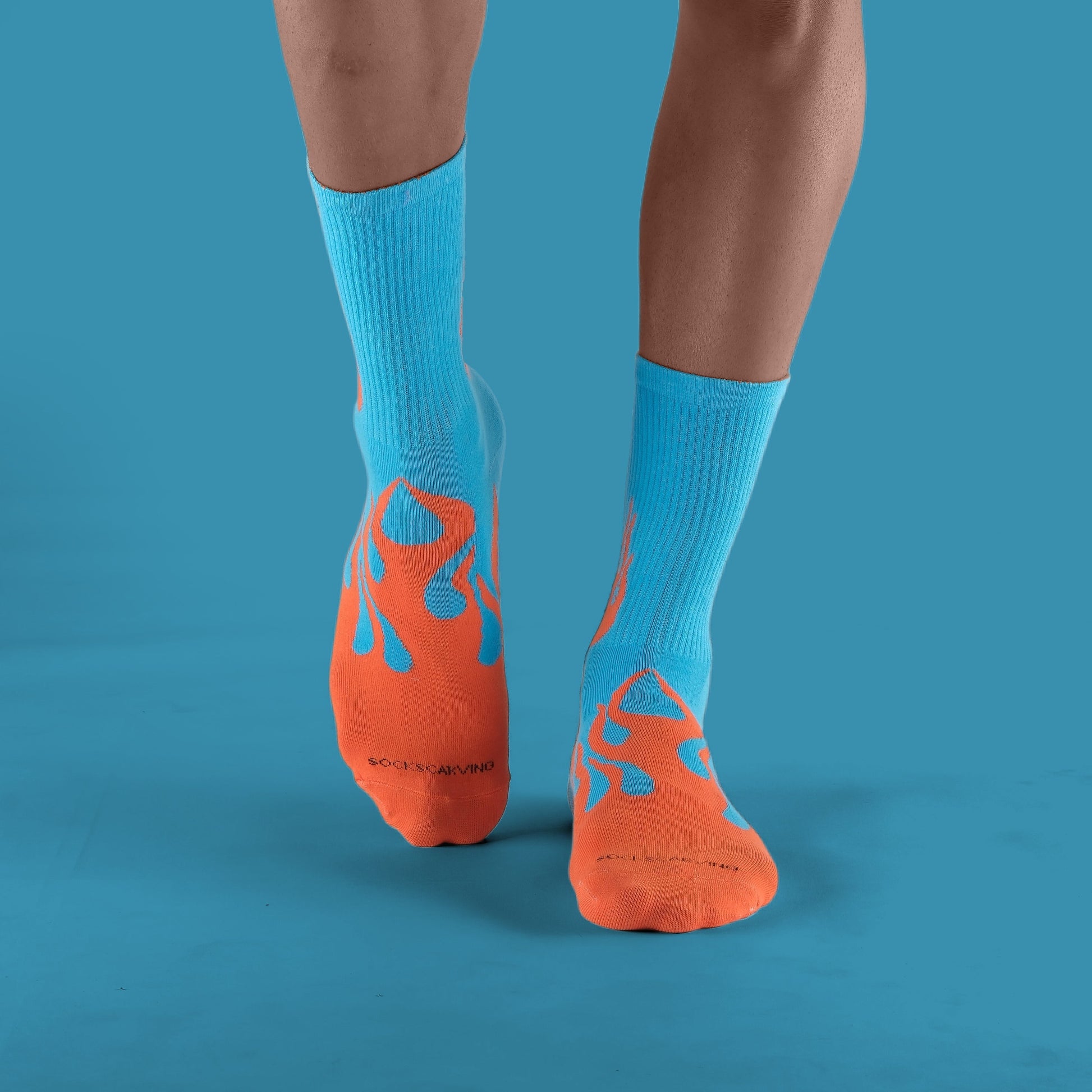Person wearing blue socks with orange flame design on a solid blue background