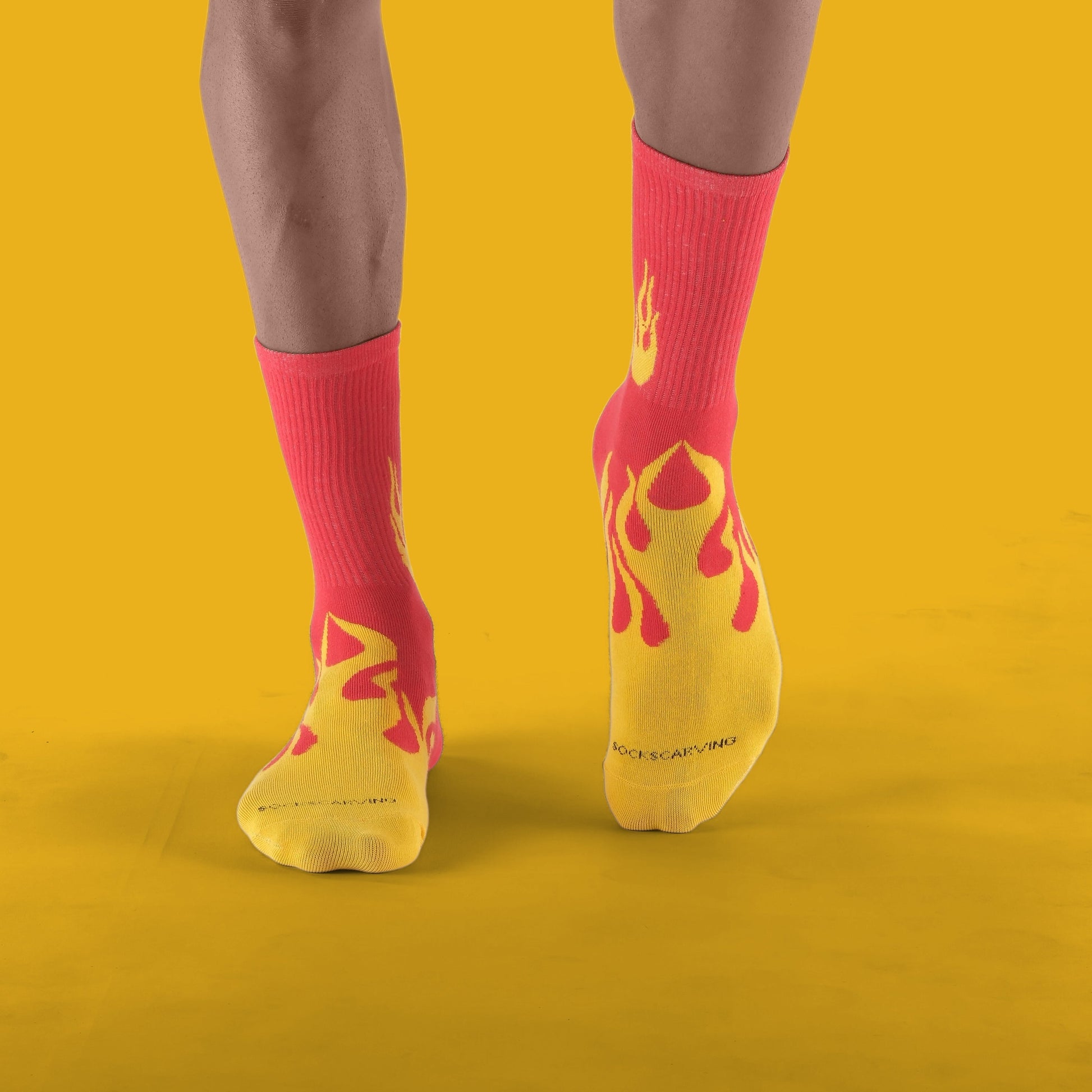 Person wearing red socks with yellow flame design on a yellow background