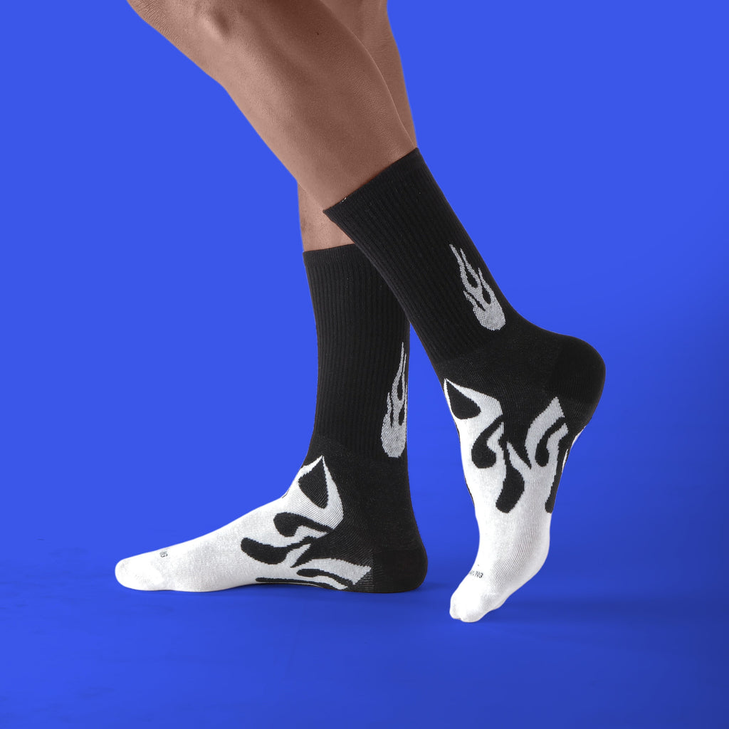 Person wearing black socks with white flame designs on a blue background