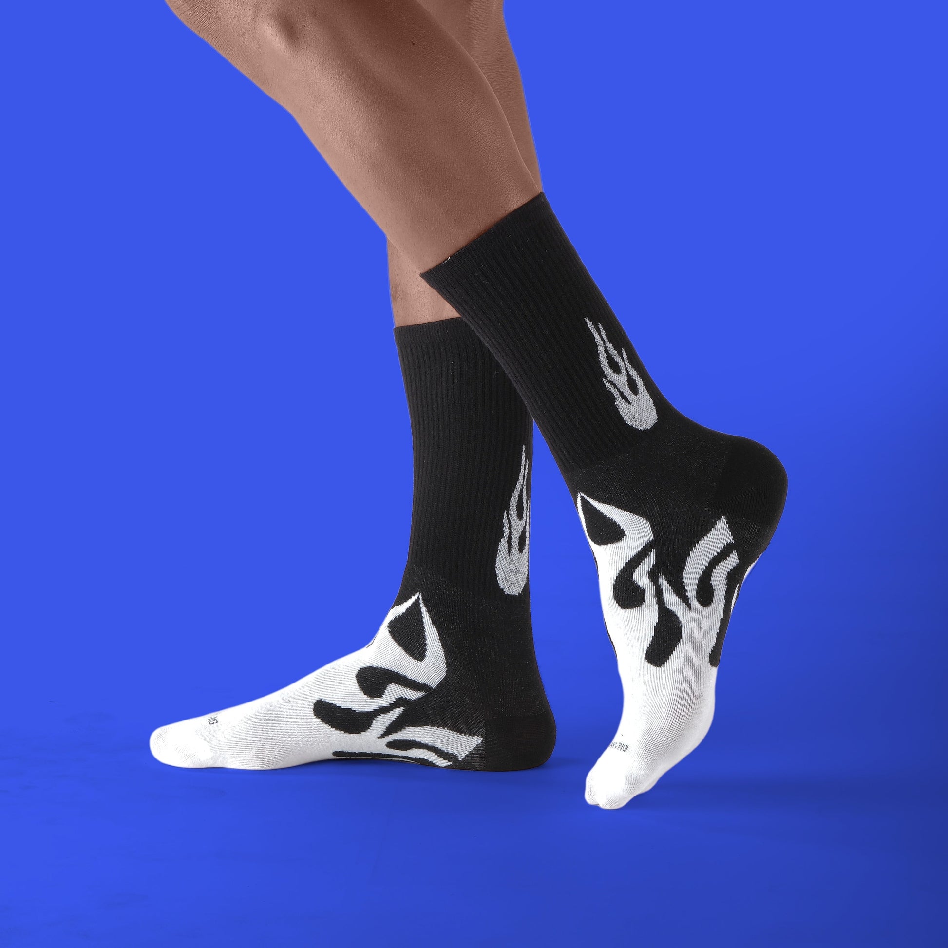 Person wearing black socks with white flame designs on a blue background
